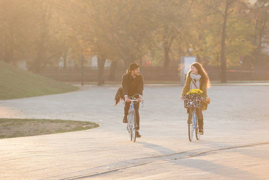Happy couple riding city bikes in the park in autumn