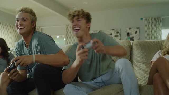 Jostling boys playing video games while girls are texting on cell phones / Cedar Hills, Utah, United States