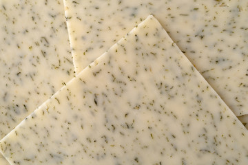 Top close view of several slices of garlic cheddar cheese.