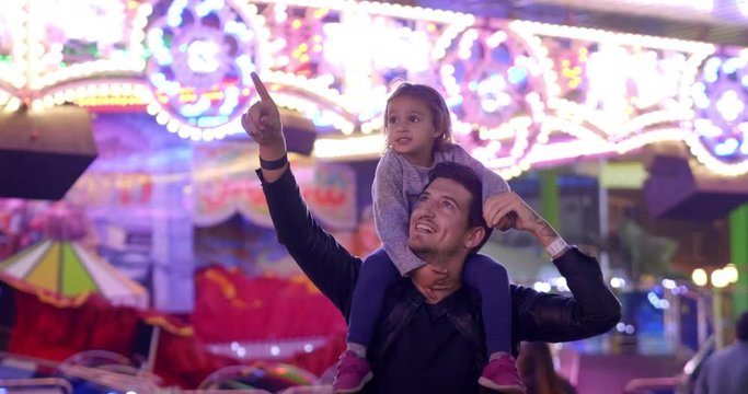 Portrait of a young father taking her daughter to the Luna Park. Concept: Happiness, freedom, fun, family