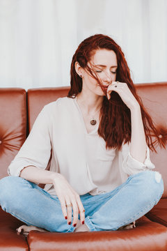 Attractive redhead woman sitting on a sofa