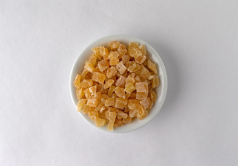 Top view of diced dried peaches in a bowl on a white background illuminated with window light.