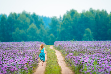 Woman runs in the field with purple flowers
