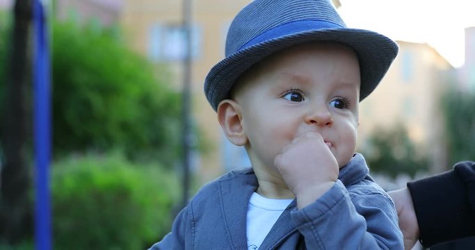 Cute Eleven Month Old Baby Boy With His Italian Hat Eating A Rice Cake Outside. Close Up View Portrait - DCi 4K Resolution

