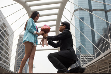 Businessman give flower bouquet to young girlfriend