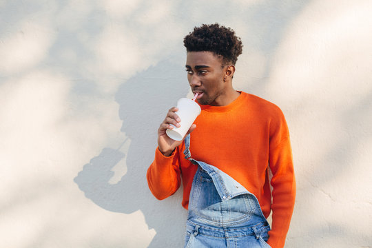 Portrait of a cool black man drinking a refreshment outdoors.