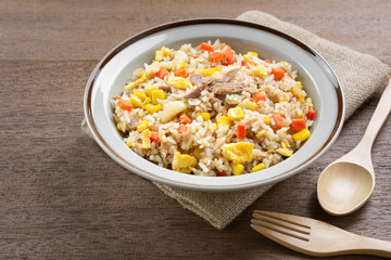 fried rice with tuna and vegetable in a ceramic dish on wooden table. homemade style food concept.