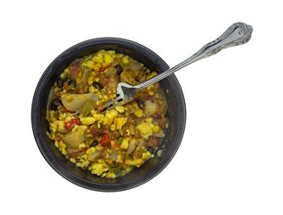 Top view of a microwaved scrambled egg burrito meal in a black tray with a fork in the food isolated on a white background.