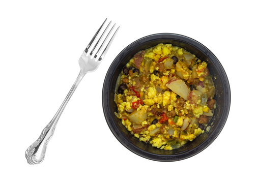 Top view of a microwaved scrambled egg burrito meal in a black tray with a fork to the side isolated on a white background.