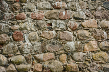 Stone wall of the old castle of granite rocks, old masonry. Texture, stonework.
