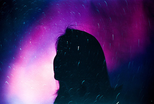 Silhouette of woman looking up at the night sky filled with stars