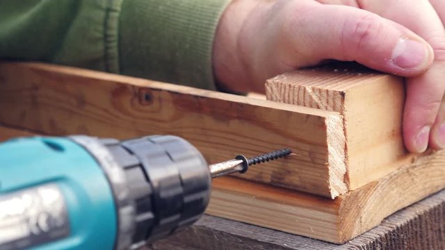 Man screwing screw in wooden plank
