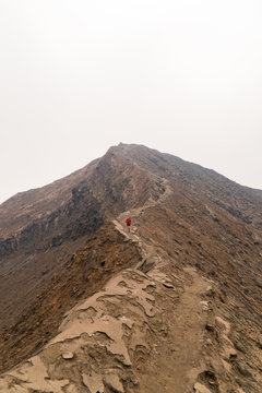A young woman hiking a ridge near a volcano