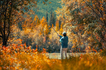 Amateur angler fishing on the autumn river - obrazy, fototapety, plakaty