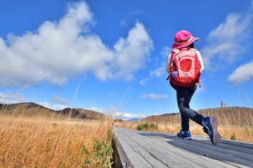青空の高原・紅葉の草原を歩くファミリー