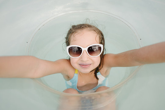 Cute young girl in sunglasses having fun with an intertube in water