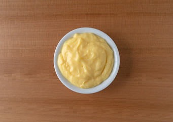 Top view of homemade banana cream pudding in a white dish atop a wood table illuminated with window light.