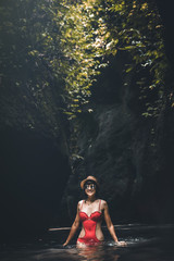 Fototapeta premium Young traveler woman in the jungle river. Rainforest of Bali island. Tourist adventure concept.