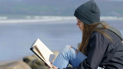 Girl enjoys reading a book at the waterfront