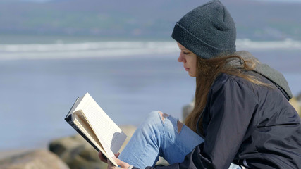 Girl enjoys reading a book at the waterfront