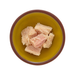 Top view of a small bowl with solid white albacore tuna in olive oil chunks isolated on a white background.