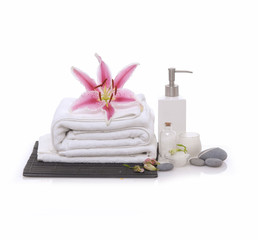 Spa setting with red orchid, rolled towel, oil, salt in bowl 