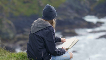 Young woman reads a book while relaxing at the waterfront