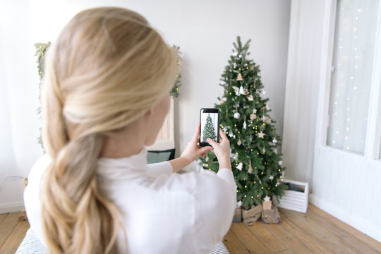 Woman taking shot of decorated Christmas tree