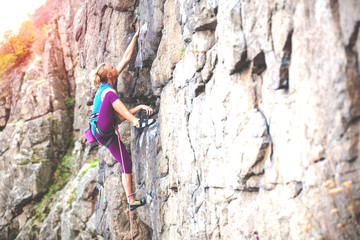 A woman climbs the rock.