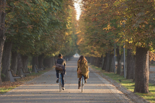 Happy couple riding city bikes in the park in autumn