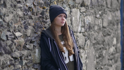 Young thoughtful woman leans against the wall