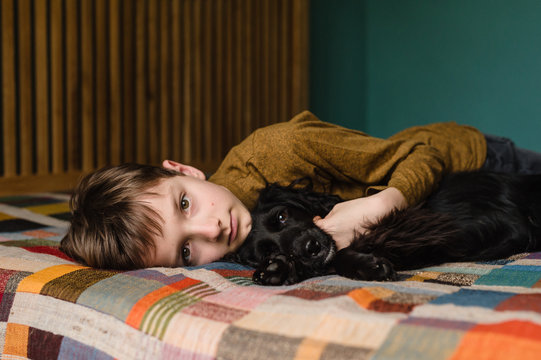 Portrait of boy with his puppy lying on bed at home