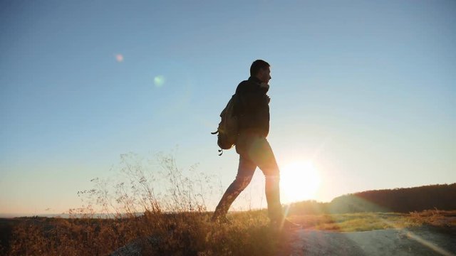 man silhouette walking tourist hiking adventure climbers sunset climb the mountain . slow motion video. hiker sunlight on top win victory the hill white rock. extreme outdoor activity sport concept