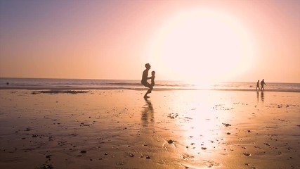 Ultra slow motion - silhouette of father and son playing together in the beach at sunset