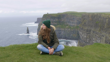 Fototapeta na wymiar Young woman travels to the famous Cliffs of Moher in Ireland