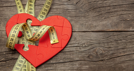 Red heart puzzle and yellow measuring tape. Overweight kills the heart. Concept Obesity. Copy space...