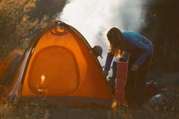Hikers set the tent and make fire in the wild area