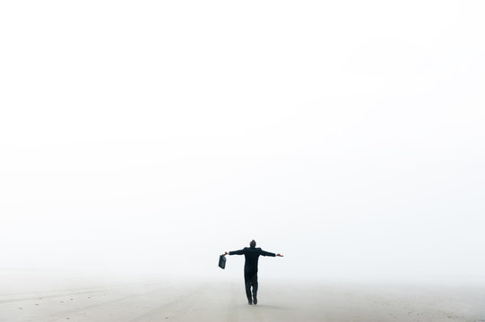 Businessman walking on a foggy beach