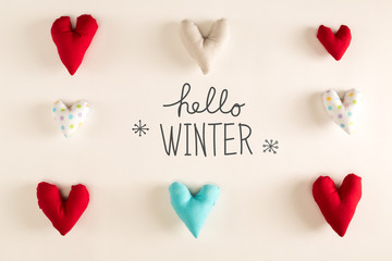 Hello Winter message with blue heart cushions on a white paper background