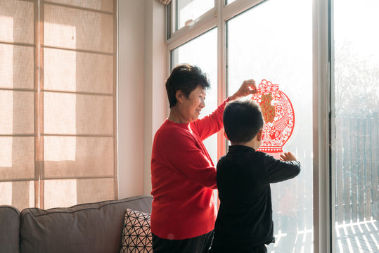 Adorable boy and his grandmother decorating for Chinese new year