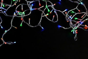 Christmas garland is burning on a black background with a toy.
