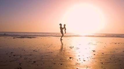 Ultra slow motion - silhouette of father and son playing together in the beach at sunset