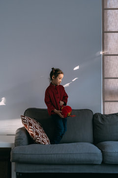 Lovely little girl in chinese custom holding a latern and jumping on sofa