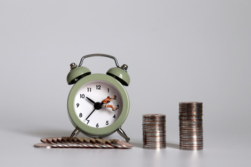 Miniature people and coins hanging on the clock hands.
