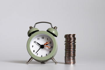 Miniature people and coins hanging on the clock hands.