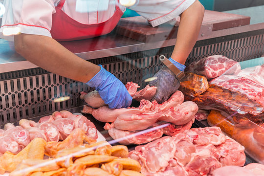 Woman preparing meat for sell on a display cabinet