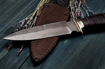 Damascus hunting knives with leather sheath on a vintage wooden background