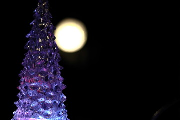 紫色に光るクリスマスツリーと満月(丸い光)