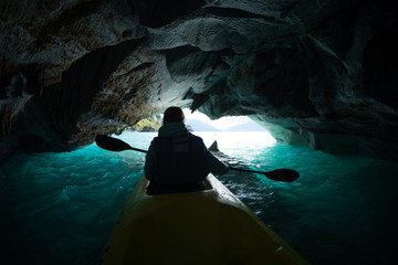 Woman paddles kayak inside the marble cave located on the General Carrera lake in Chile