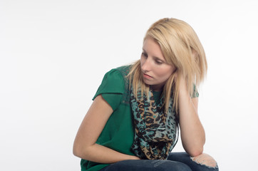 Pretty, young, blonde woman, sitting, hand in hair, looking away